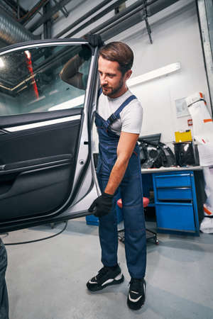 Mechanic taking off a door of automobileの写真素材