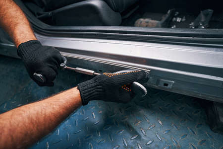 Person holding straightening tool pressed to car side door frameの写真素材