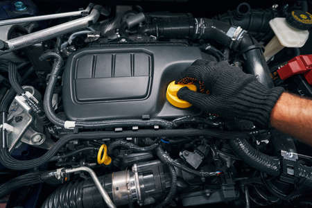 Worker removing oil filler cap of engine