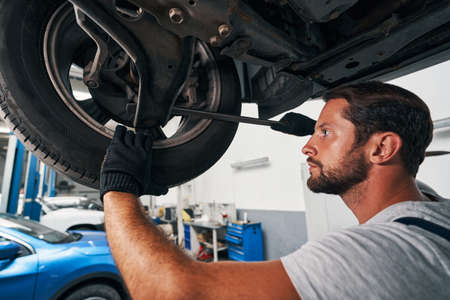 Male specialist checking car suspension with crowbarの写真素材