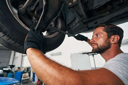 Man performing suspension system check using crowbarの写真素材