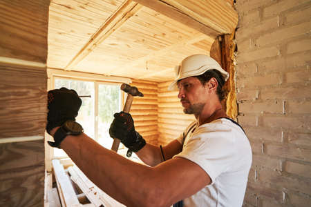 Man spiking nail with hammer into wallの写真素材
