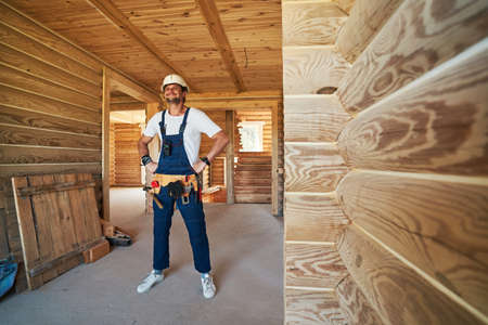 Satisfied construction worker with tool belt looking ahead