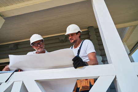 Designing engineer and worker looking through house layout