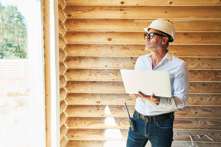 Distracted engineer with laptop staring outside from house