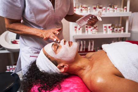 Close up of cosmetologist applying clay maskの写真素材