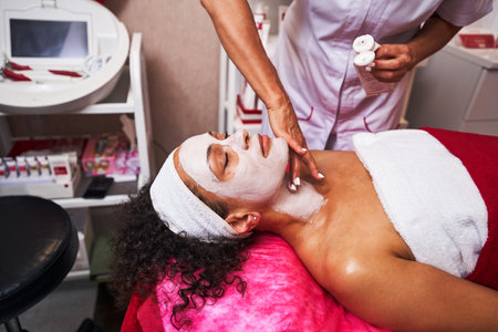 Focused photo on cosmetologist putting clay maskの写真素材