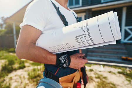 Housebuilder carrying blueprints and tools with himの写真素材