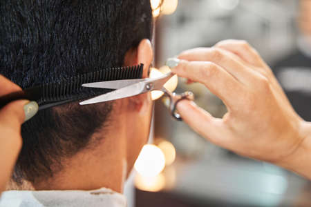 Person doing haircut to client with scissorsの写真素材