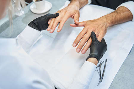 Manicurist taking client hands and inspecting nailsの写真素材