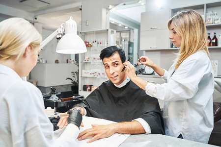 Male getting haircut and nail polishing from womenの写真素材