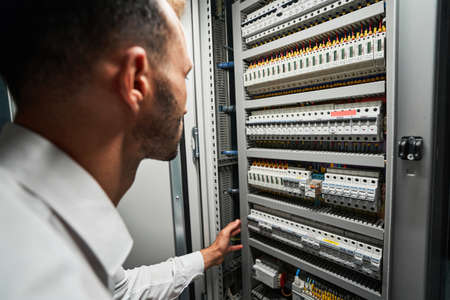 Data center worker reaching for electrical switch inside cabinetの写真素材