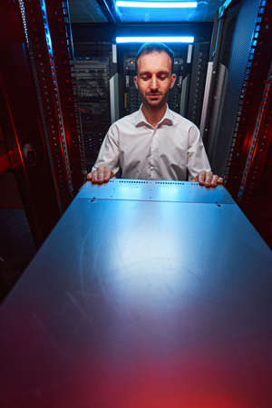 Pleased network administrator looking at server cabinet