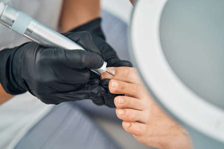 Close up of master removing cuticle from nailの写真素材