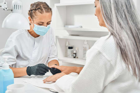 Concentrated nail master looking at hands of client