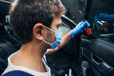 Worker cleaning panel under car window with brushの写真素材