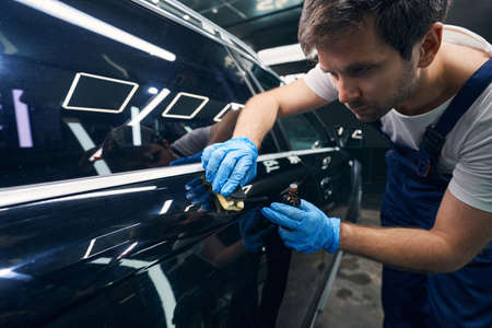 Attentive worker smearing blemishes on auto surface with ceramic coatingの写真素材