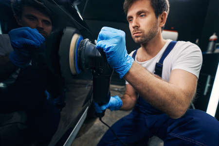 Male with hand sander taking care of car surface