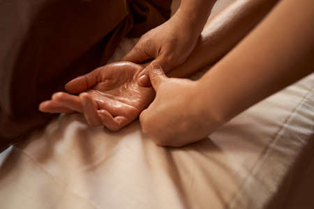 Massage therapist stimulating reflex point on client handの写真素材