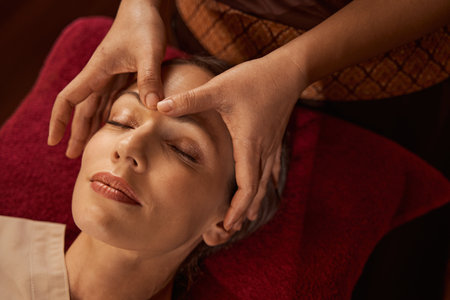 Relaxed Caucasian female client napping during facial acupressureの写真素材