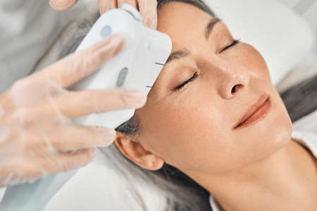 Close up of cosmetologist holding laser machine
