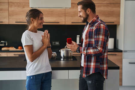 Bearded male proposing to his happy lady in their modern home apartments