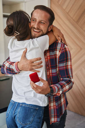 Bearded adorable man proposing to beautiful lady in the home apartmentsの写真素材
