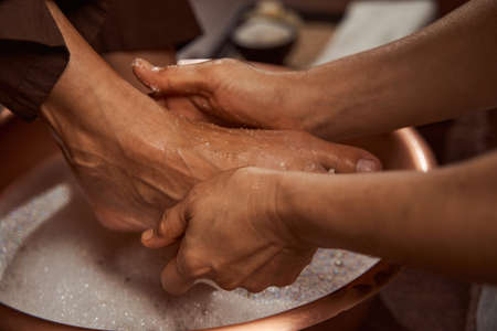 Beauty salon worker rubbing her client feet with sea saltの写真素材