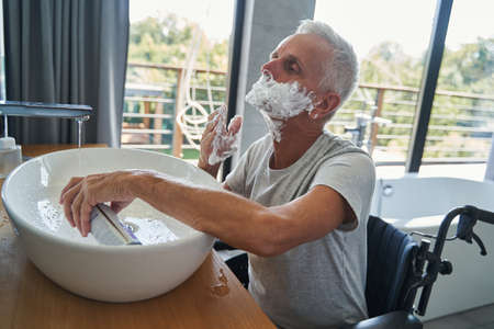 Disabled pensioner applying shaving cream on his faceの写真素材