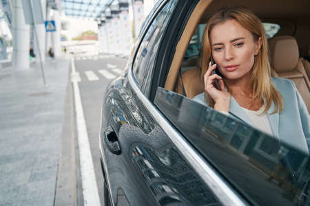 Female passenger calling on smartphone in taxicab