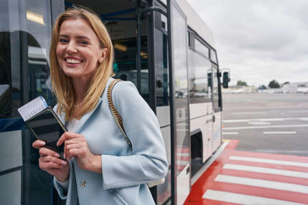 High-spirited tourist posing against beside parked airport shuttle bus