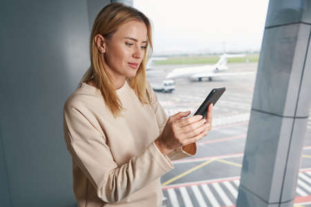 Concentrated tourist using her cellphone in waiting area