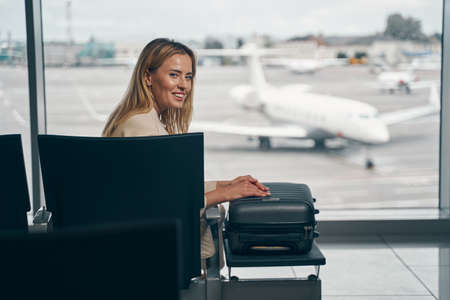 Cheerful traveler with luggage sitting in airport loungeの写真素材