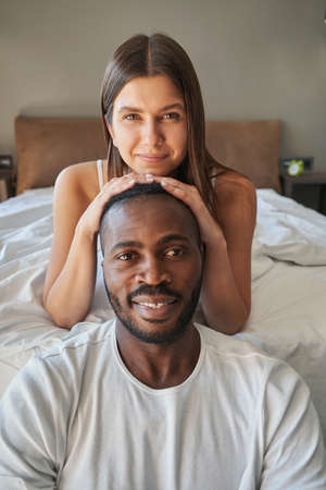 Young female lying on bed behind happy male
