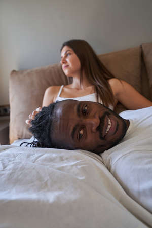 Joyous guy posing for camera with pensive lady on backgroundの写真素材