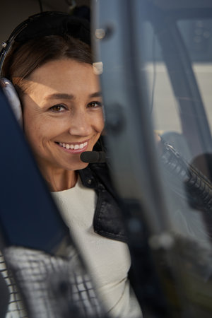 Joyful woman in safety headset posing in copter cockpitの写真素材