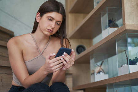 Focused serious lady reading text message on cellphone