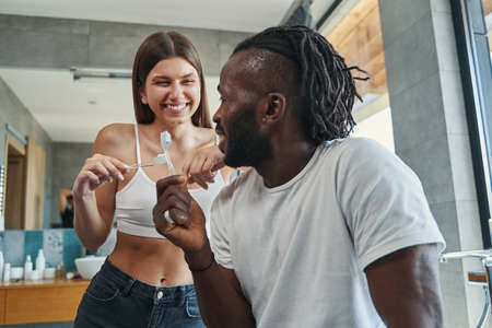 Cheerful couple with toothbrushes in hands gazing at each otherの写真素材