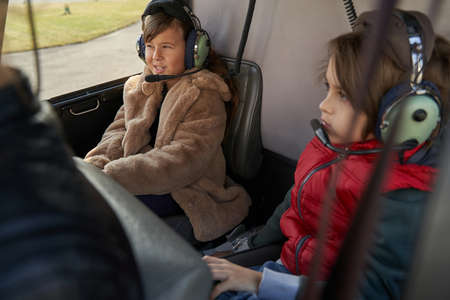 Kids in protective gear having a flight on a helicopterの写真素材