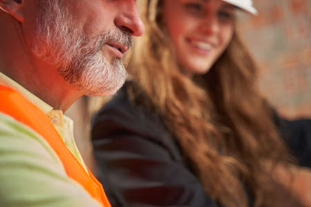 Two people in hardhats and visibility vests posing for camera