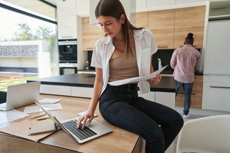 Concentrated woman with documents using her notebook computerの写真素材