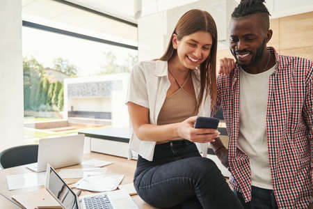 High-spirited female showing something on smartphone to pleased man