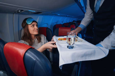 Woman accepting airline dinner from flight attendantの写真素材