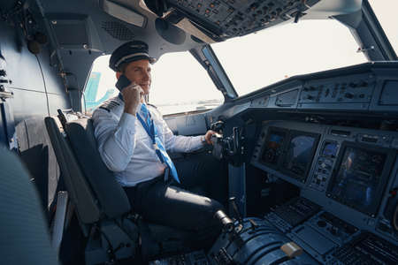 Plane captain talking on the phone in cockpit