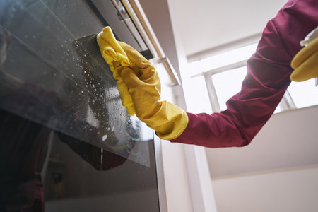 Professional janitor cleaning part of electric rangeの写真素材
