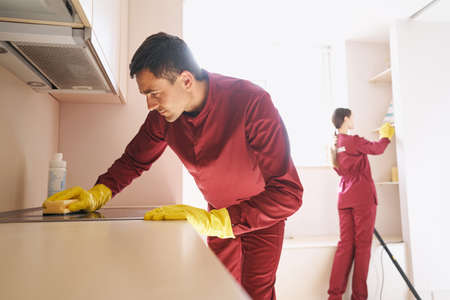 Team of uniformed Caucasian janitors cleaning kitchen