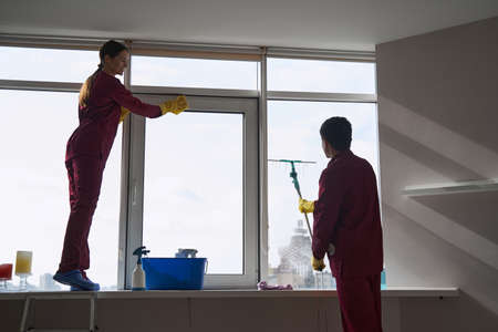 Janitorial staff using microfiber cloth and squeegee for window washingの写真素材