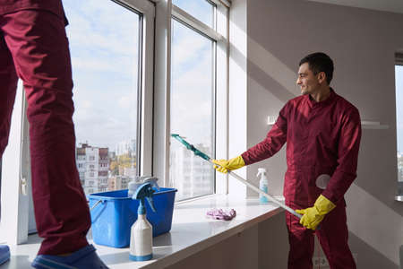 Experienced janitorial personnel in uniforms washing windowの写真素材