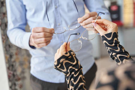 Cropped photo of two people comparing pairs of eyeglassesの写真素材
