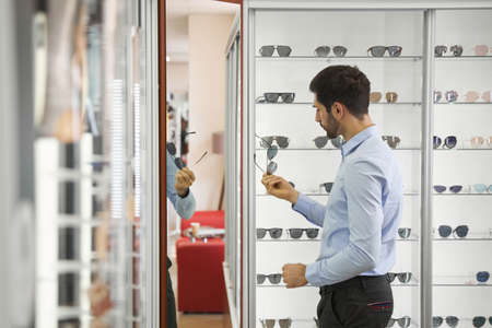 Man studying sunglasses in showroom of optician shop